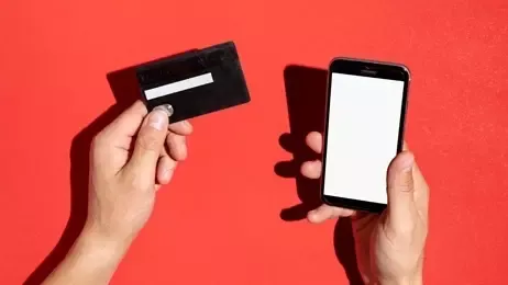 ผู้ชายถือบัตรเครดิตและโทรศัพท์มือถือ