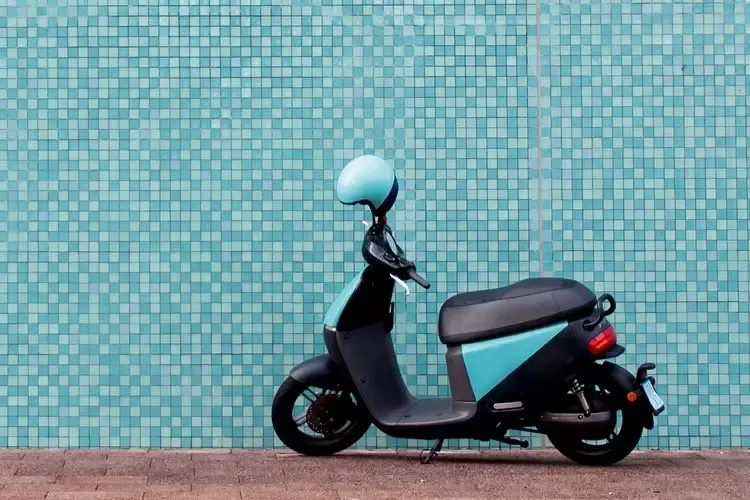 รถสกู๊ตเตอร์สีฟ้าจอดข้างกำแพงสีฟ้า 
