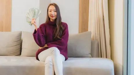 ผู้หญิงถือธนบัตรนั่งบนโซฟา